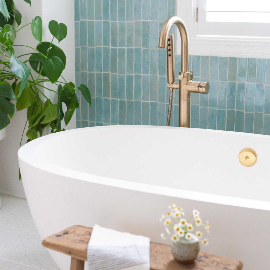 Modern bathroom with freestanding bathtub, blue zellige tiles, and decorative elements.